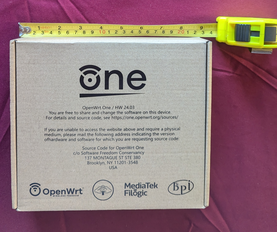 openwrt one box with tape measure for scale